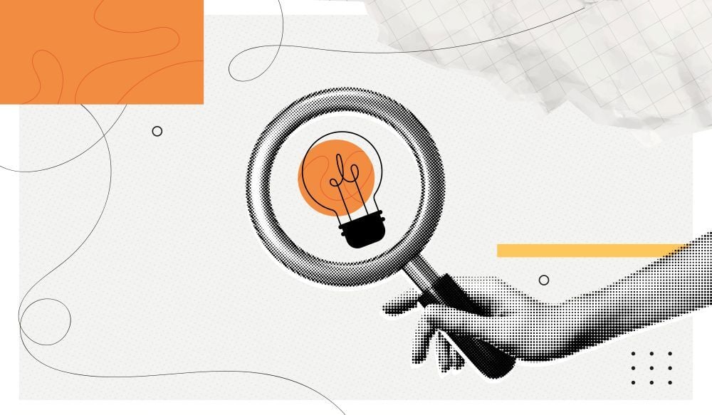 Hand holding magnifying glass with lightbulb.