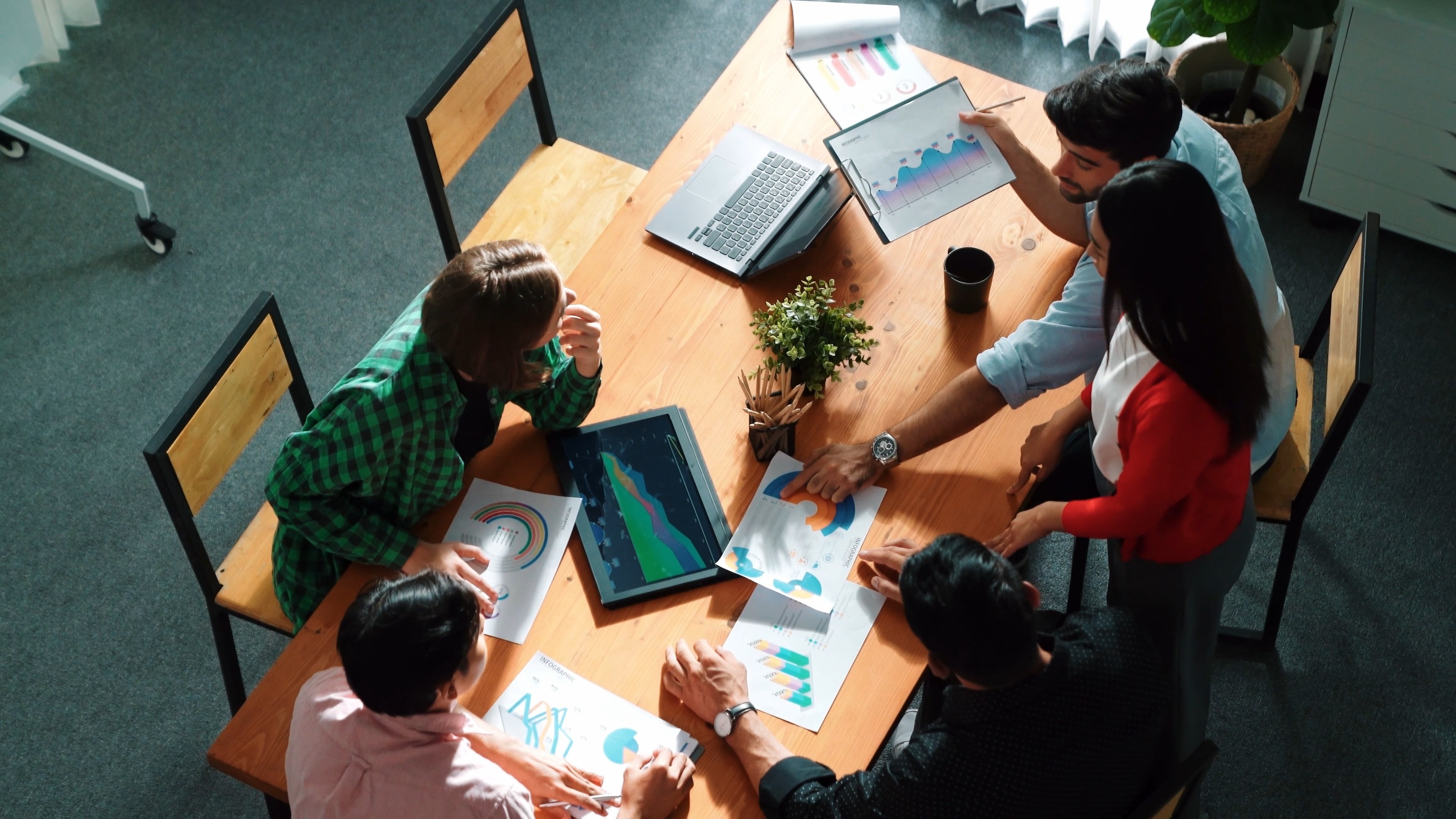Team brainstorming financial idea while looking at financial statistics from laptop.